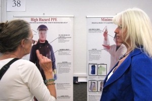 University Research Council judge Mary O’Connell, left, discusses a poster representing a research project titled “Minimum Lab PPE (Personal Protective Equipment),” by Katrina Doolittle, right, and David Schoep, not pictured, of the Department of Facilities and Services. 